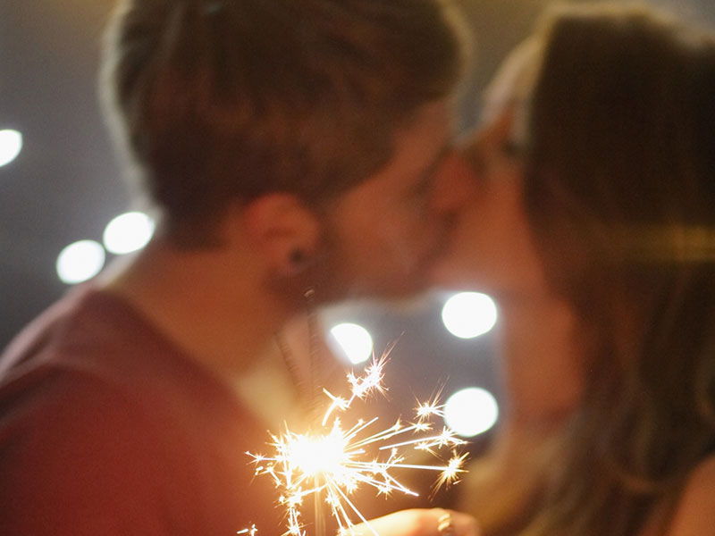 A couple kissing while holding sparklers.