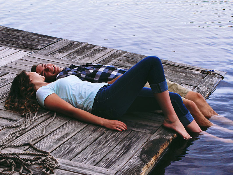 A guy and a girl looking at each other while on a pier.