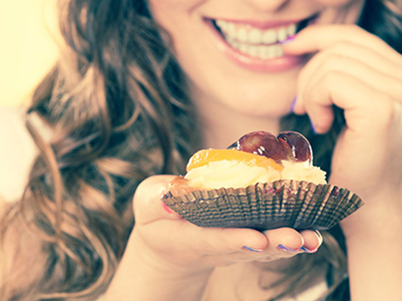 A woman looking sexy while eating a pastry.