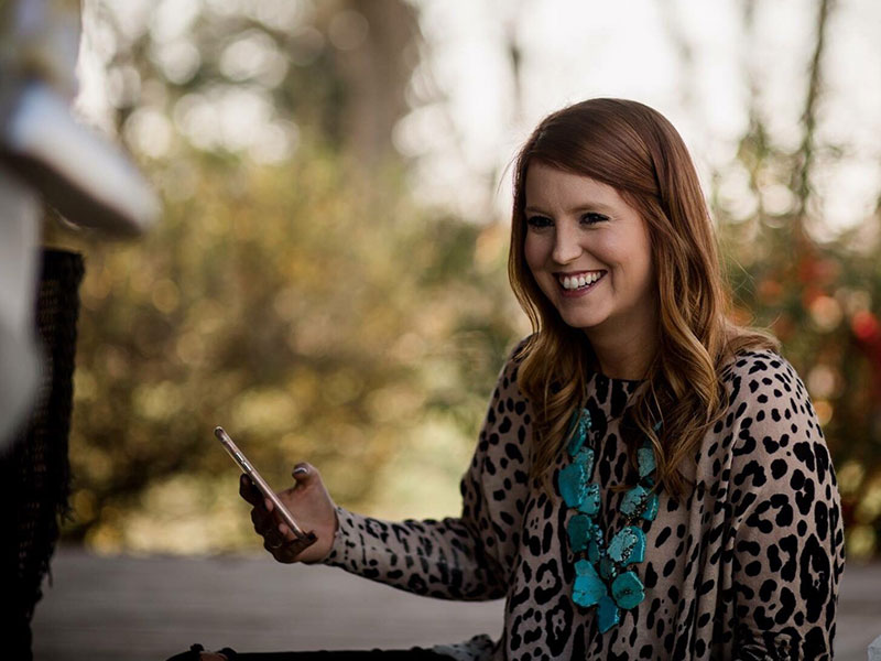 A woman learning how to date after taking a long break laughing while using her phone.