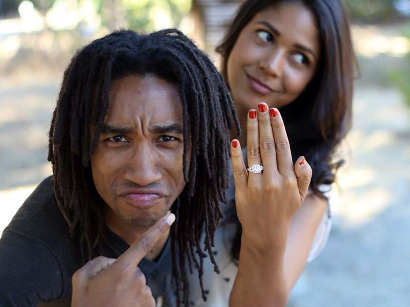 A couple who just got engaged goofing around and pointing at their ring because their love will last.