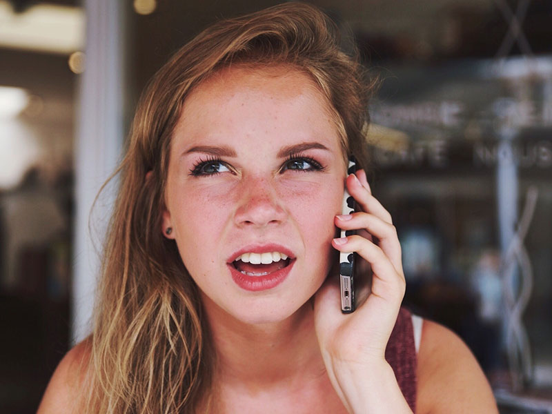 A girl on the phone who is confused about outdated dating rules like the three day rule.