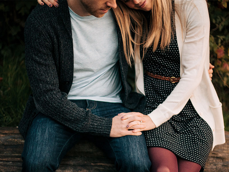 A woman who's dating someone who doesn't want to get married holding his hand while they talk in a barn.