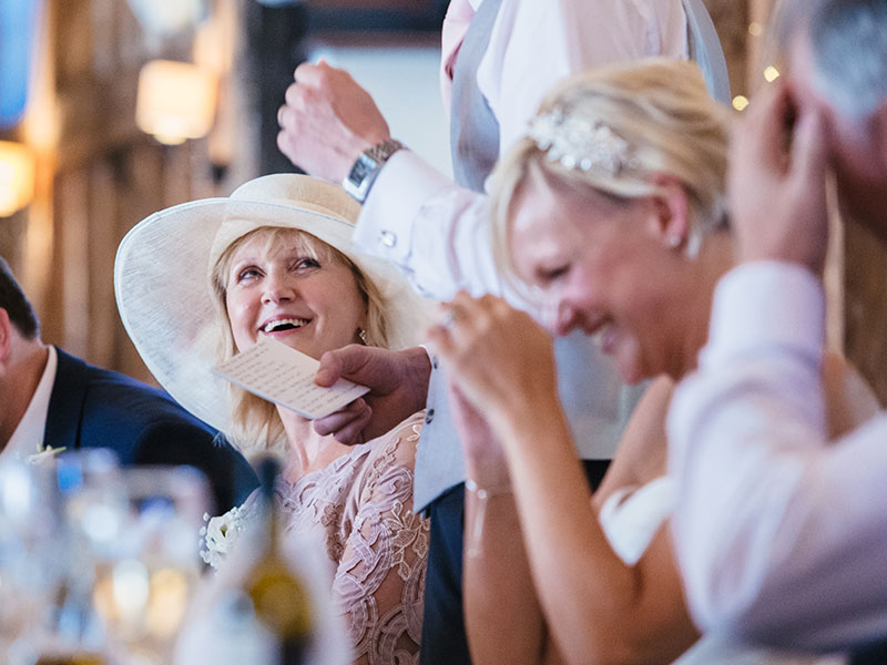 A crowd at a wedding laughing after the maid of honor speech.