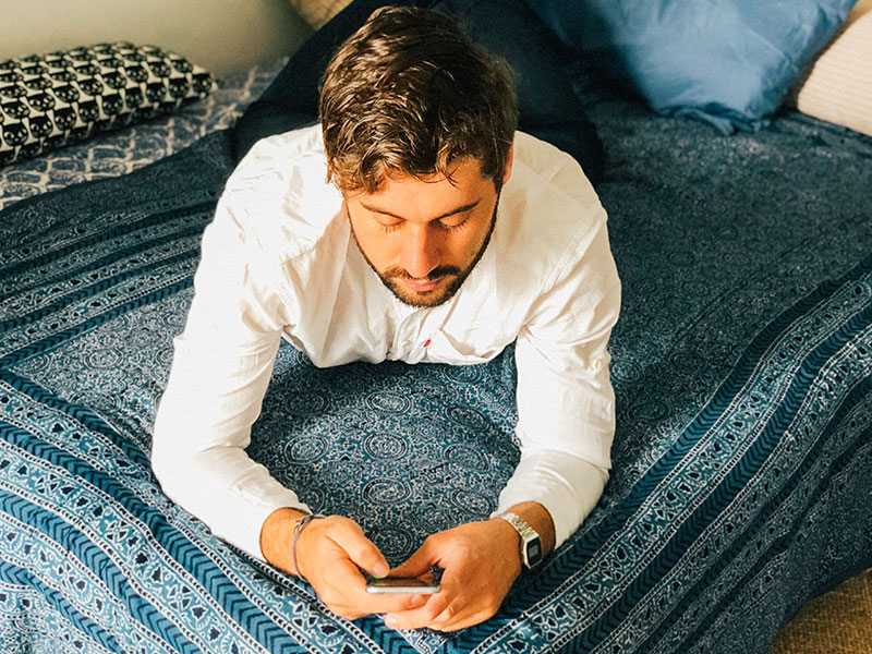 A man texting a woman he met using these online dating tips for men while lying in bed.