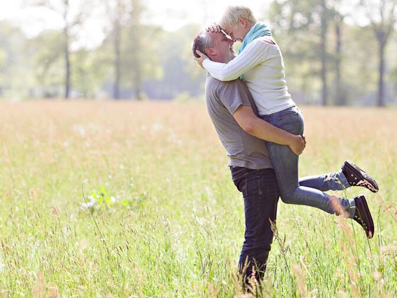 A couple dating after 50 hugging in a field and smiling.