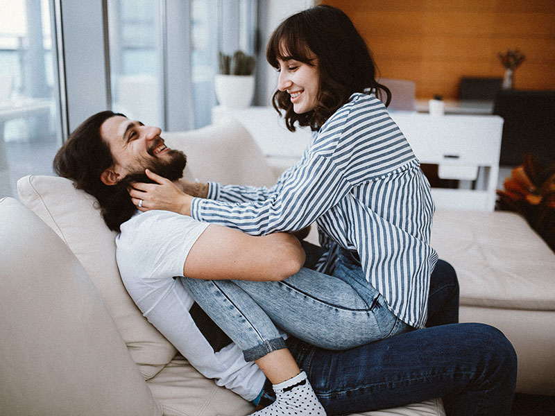 A guy who used one of these flirty quotes for her laughing while his girlfriend sits on his lap and teases him.