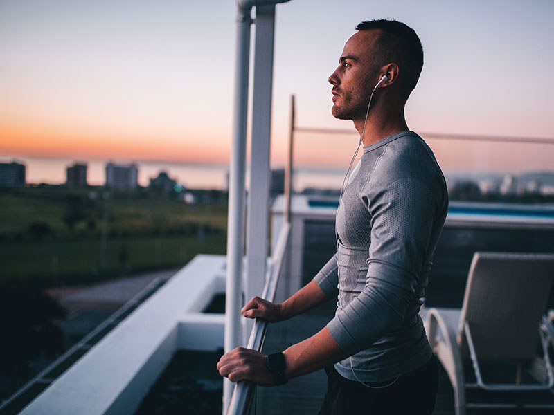 A man who's working on personal growth after a breakup looking out at the sunset at the end of his run.