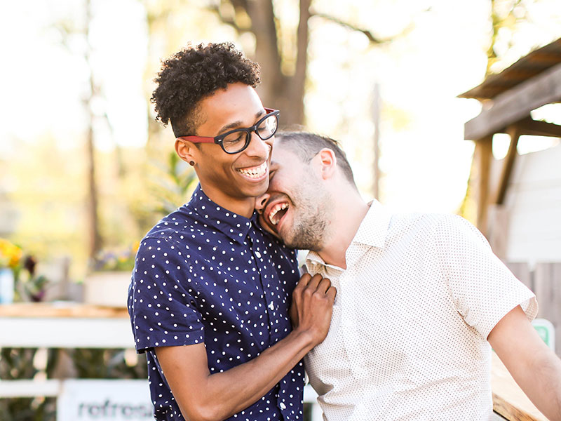 A gay couple who thought they were too busy to date, smiling and laughing together on their first date.