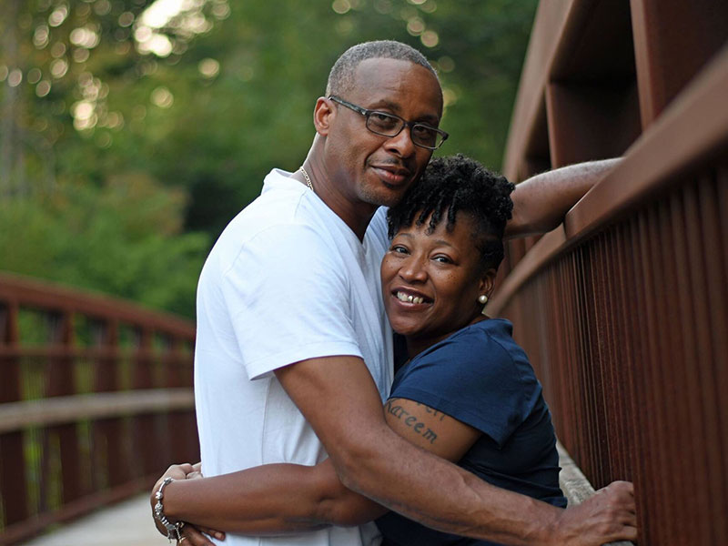 A women who was dating single men over 50, hugging her boyfriend on a deck in the woods.