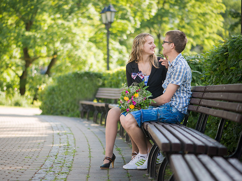 A guy who learned what does benching mean sitting on a bench with the girl he's dating chatting.