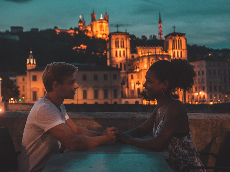 A woman using these personal questions to ask a guy, on a date with her boyfriend asking him questions as they hold hands.
