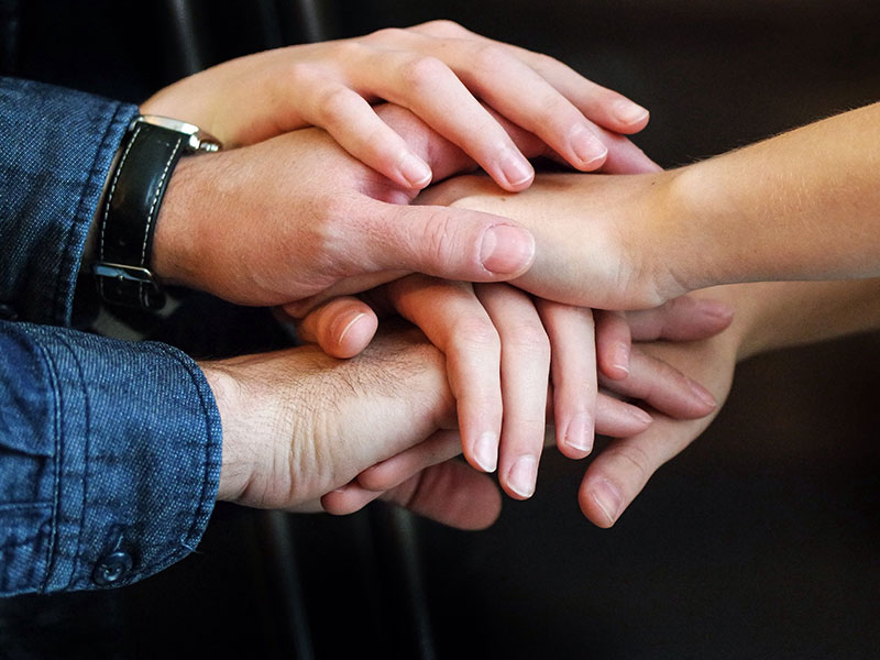 Three people in a triad relationship holding hands.