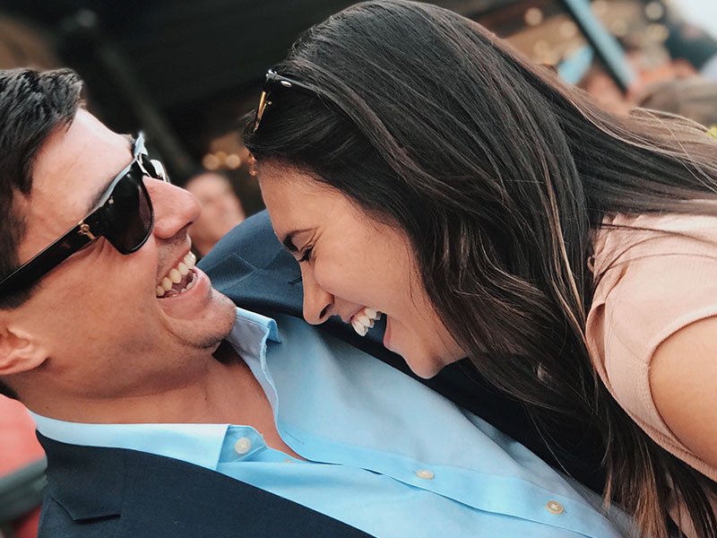 A couple who are dating outside their type laughing in a crowd.