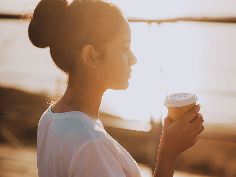 A woman with a fear of relationships after divorce drinking coffee and watching the sunrise.