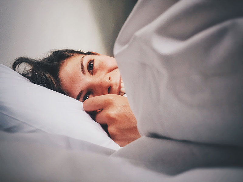 A woman in bed laughing because she doesn't know what the definition of a hookup is.