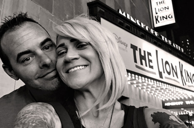 A couple smiling in front of a theatre because they took advantage of this winter date ida.