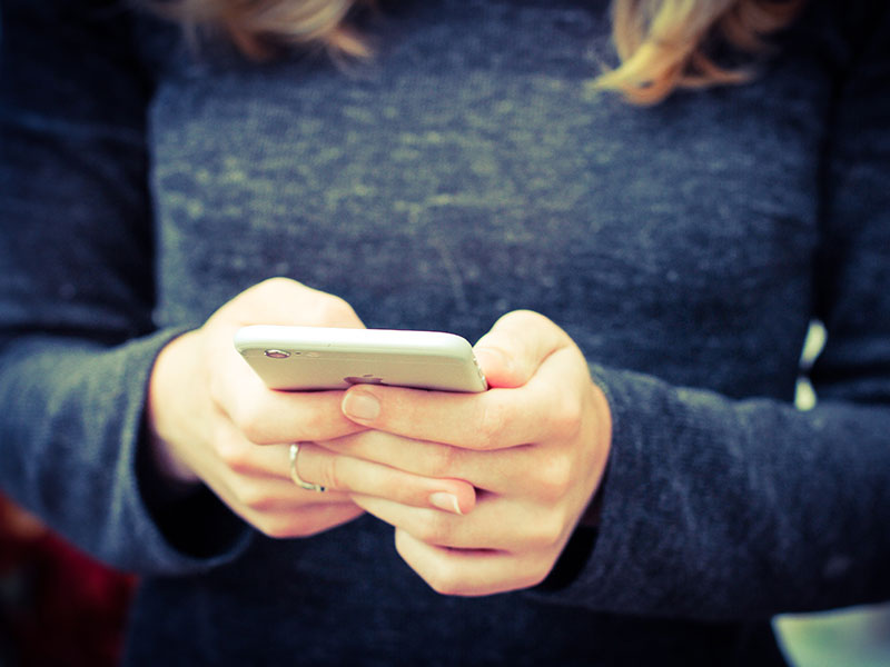 A woman breaking up over text, trying to think of what to say while outside on her phone.