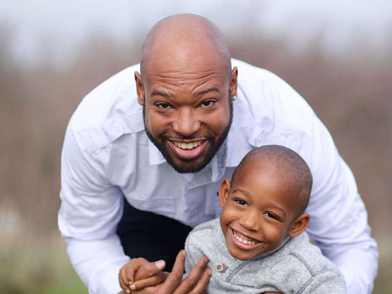A dad who is dating someone with kids, playing with their kid and laughing in a field.