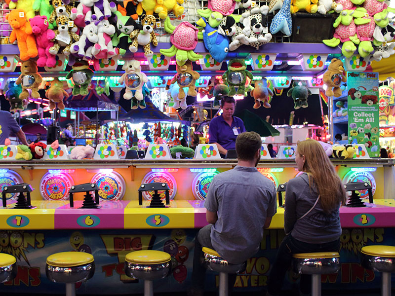 A couple trying to win a stuffed animal at the fair--one of these places to go on a date.