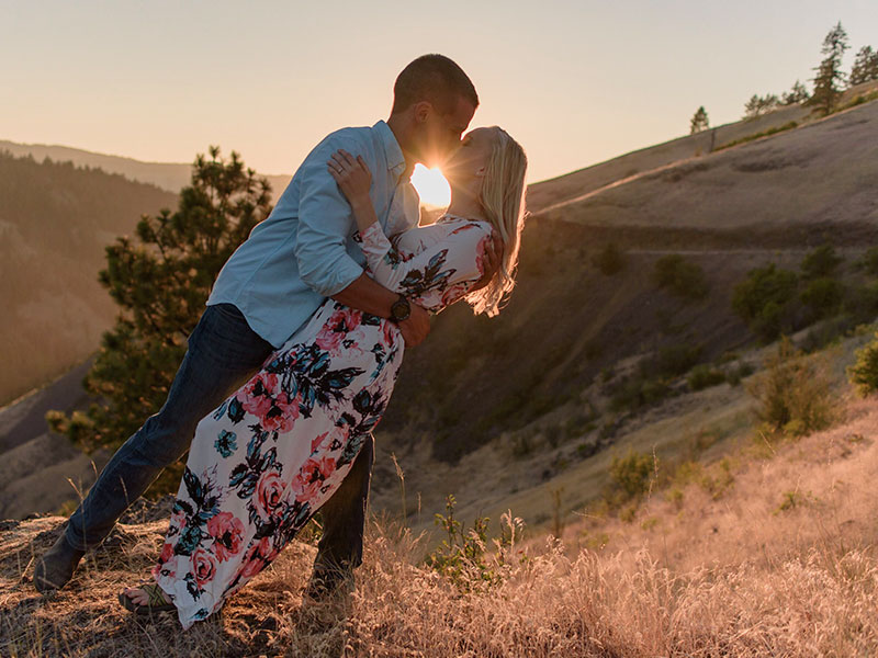 A couple who used one of these anniversary date ideas kissing at sunset.