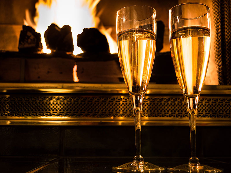 Two champagne glasses in front of a fire, one of these at home date night ideas.