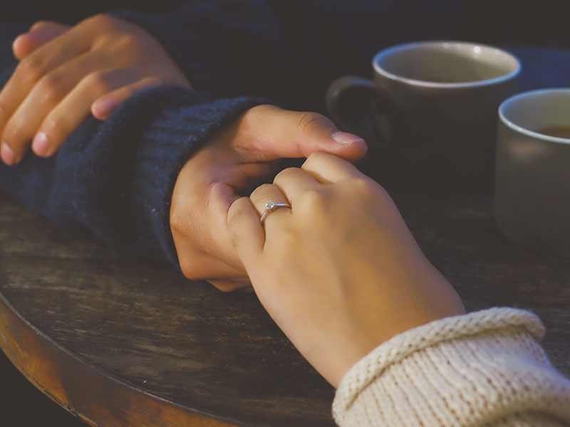 A couple who has strong trust in a relationship, holding hands over a table.