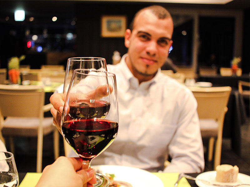 A guy on a first date cheersing his date across the table.