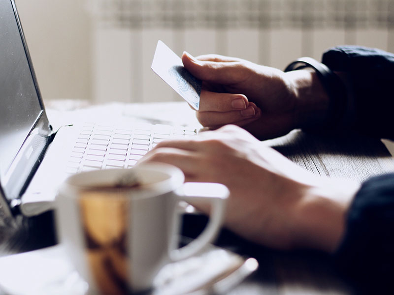 A person talking to an online dating scammer about to share their credit card information while sitting at their computer.
