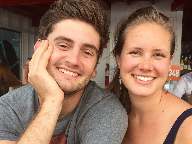 A guy and a girl in a platonic friendship smiling as they sit at a table together.