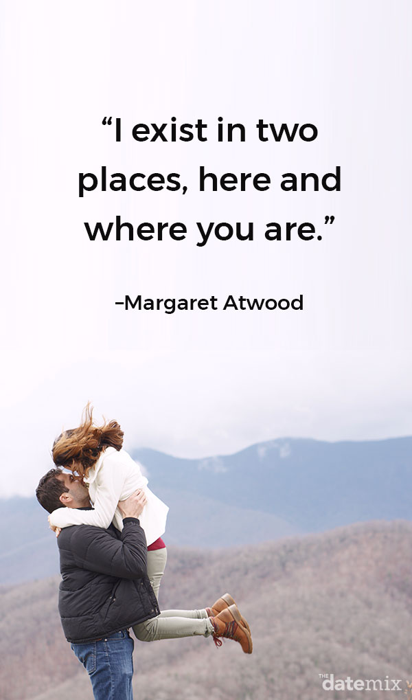 A woman and man hugging on a mountain with the long-distance love quote below written in the sky.