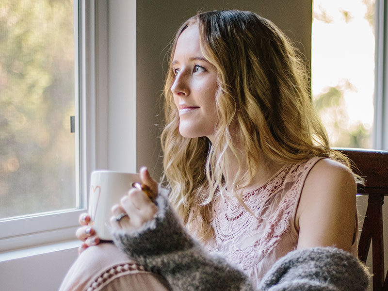 A woman who read these long distance love quotes, looking out the window and thinking of her boyfriend.