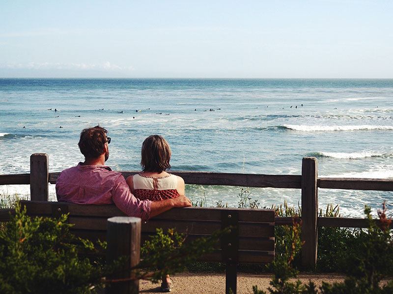 A couple talking about the man's ex while sitting on a bench.
