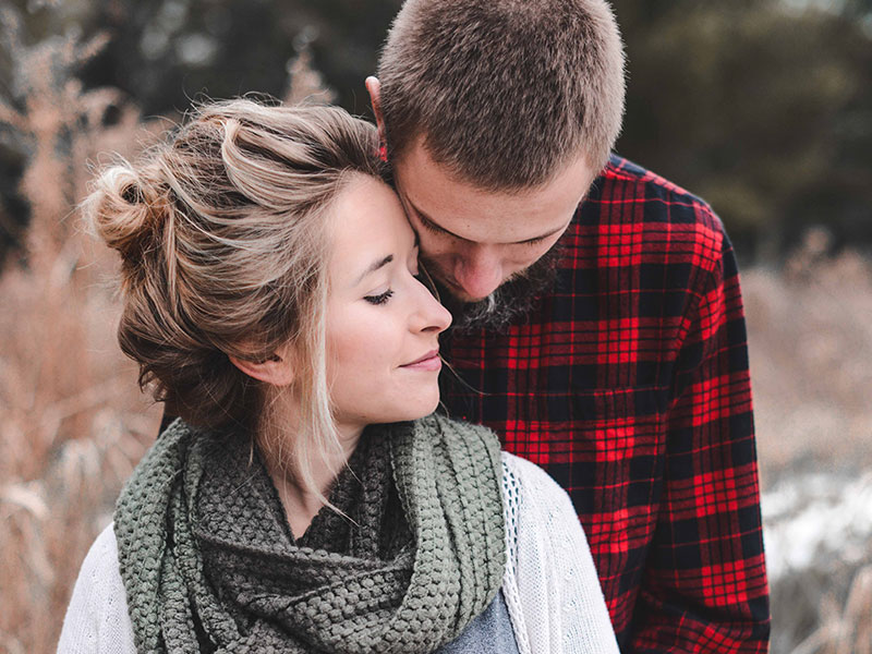 A couple who shows strong emotional intimacy canoodling outside.
