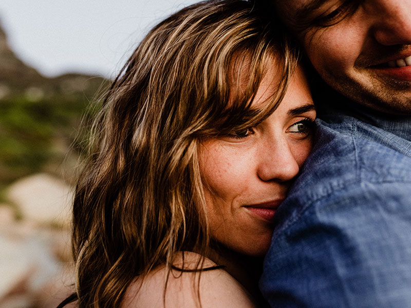 A woman who's a serial monogamist hugging her boyfriend tightly on the beach.
