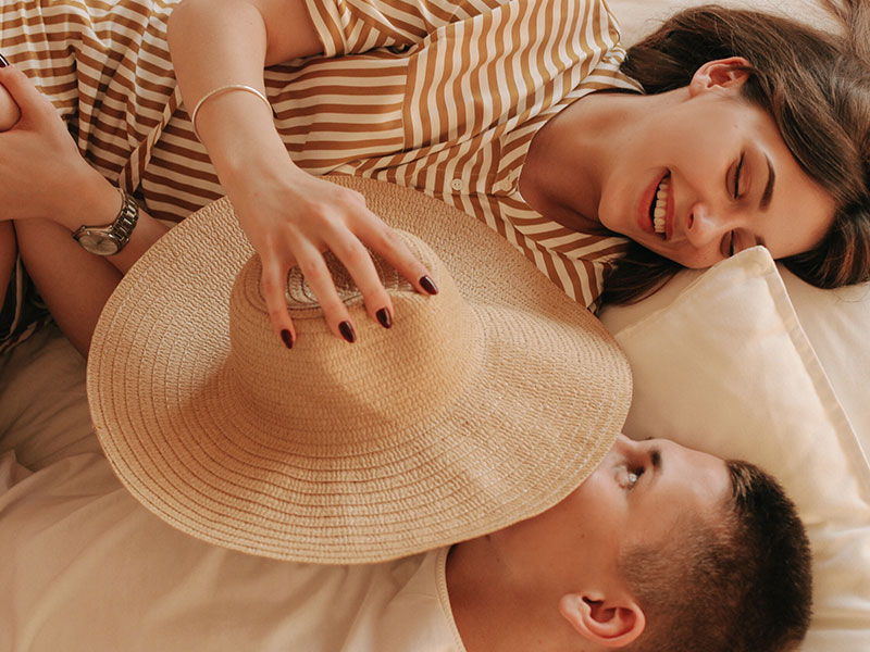 A couple laughing and teasing each other in bed.