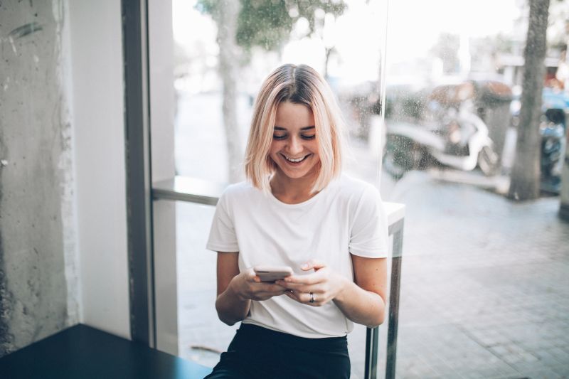 woman laughing after getting flirty text messages for her
