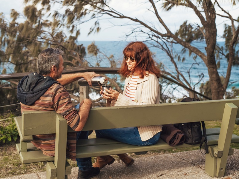 man and woman drinking coffee on bench enjoying +40 dating