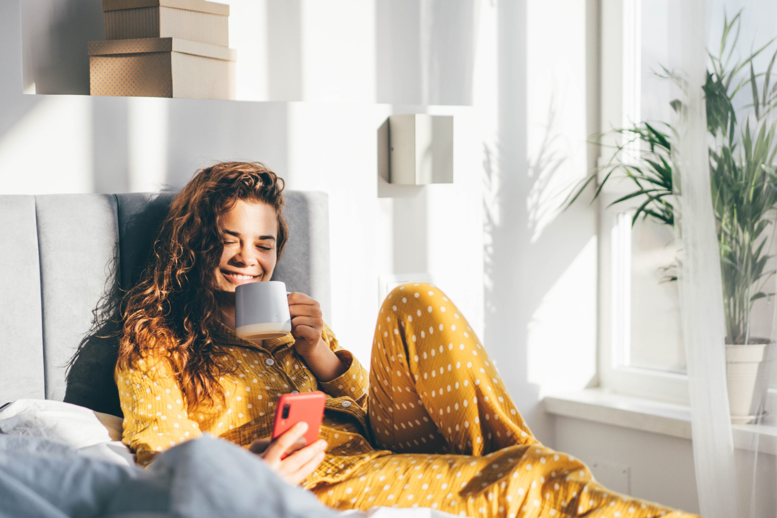 attractive woman lying in bed on her phone using one of the best dating apps for relationships, Zoosk