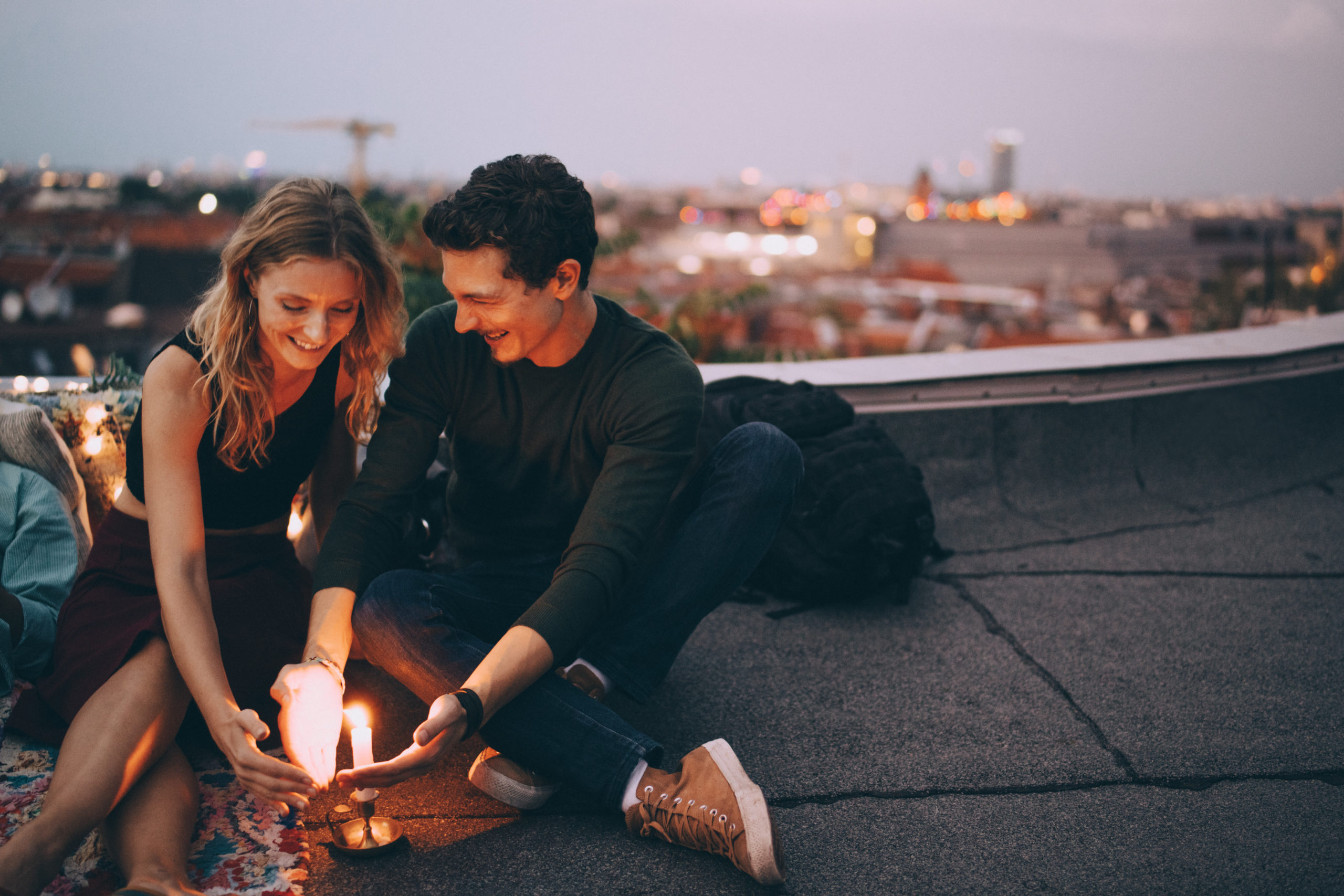 Happy, smiling couple sitting around a candle while on a date at a romantic place to visit.