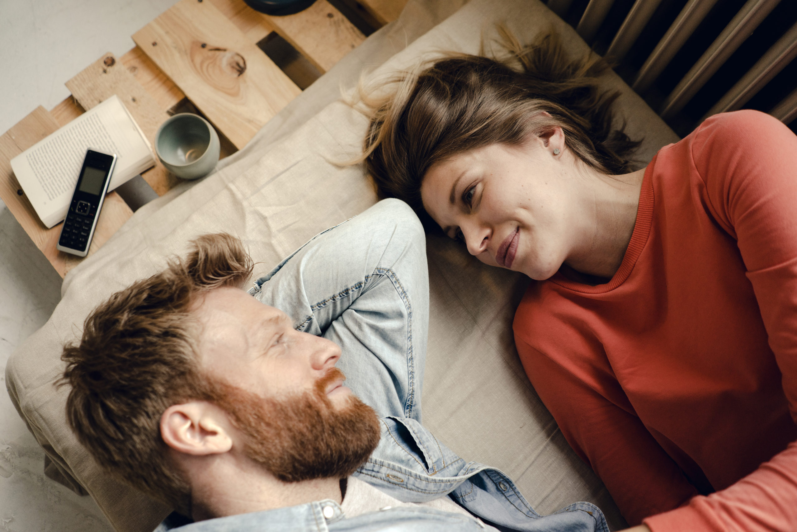 Romantic couple lying down and facing each other while sharing some romantic quotes about love.