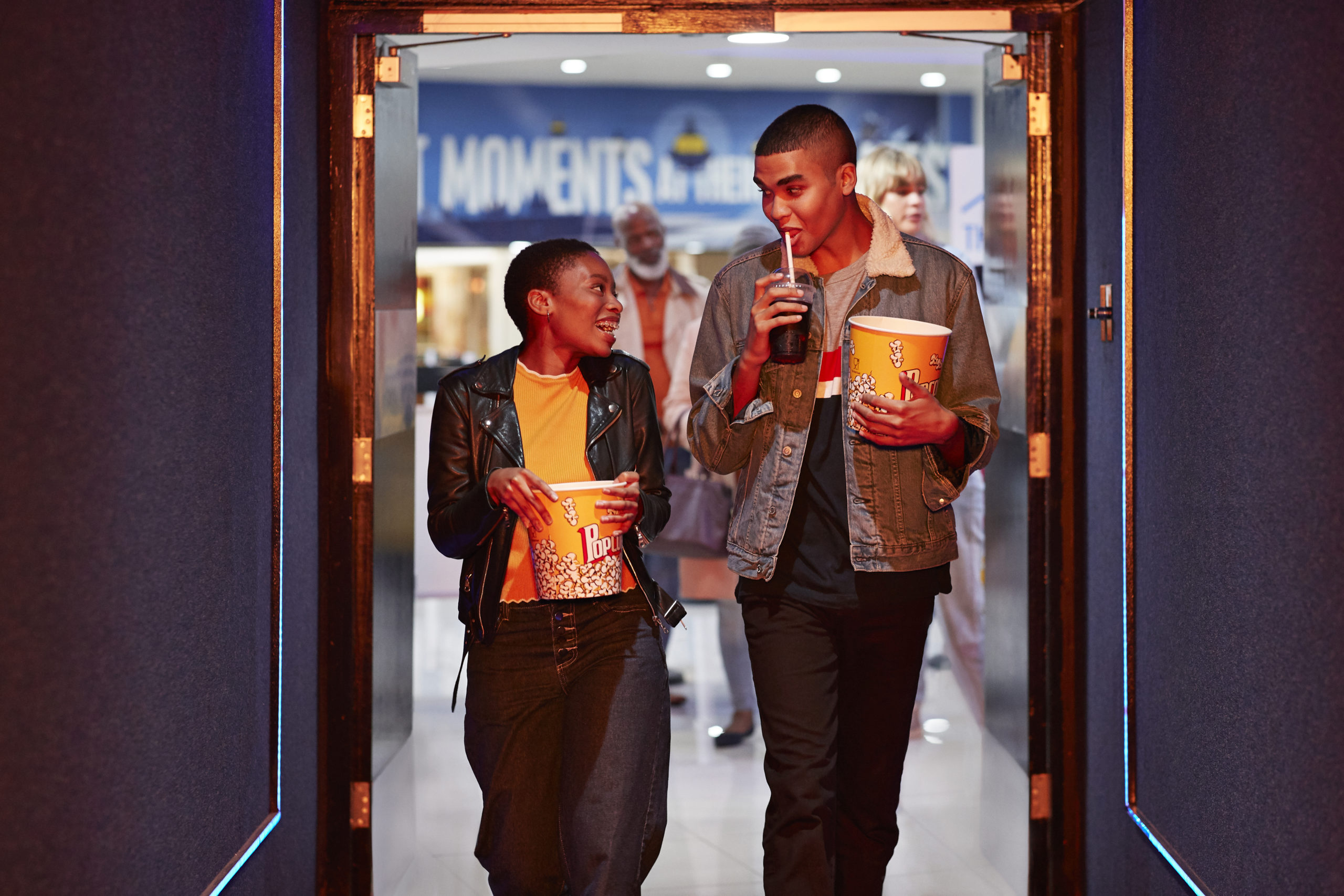 Happy young couple holding popcorn in a movie theatre after watching on Oscar-winning romance movie.